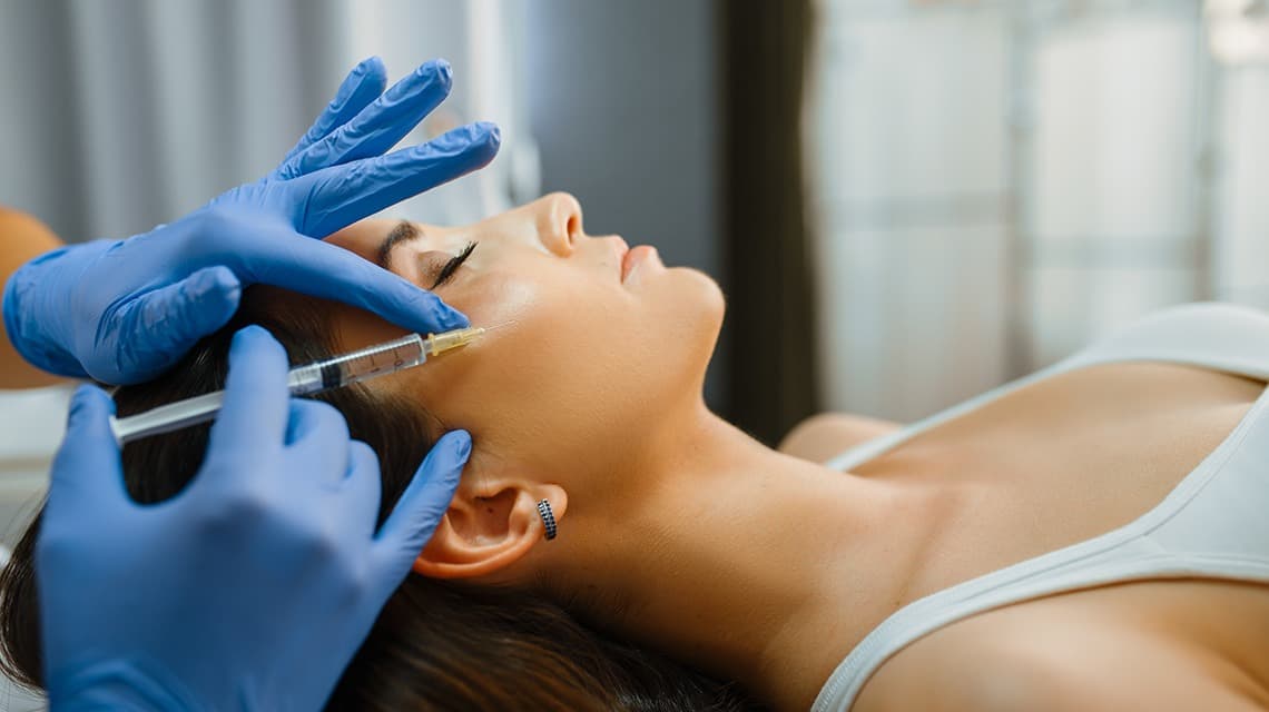 Un médecin esthétique s'apprête à injecter des produits anti-âge dans le visage d'une patiente