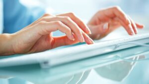 Mains de femme tapant au clavier pour illustrer les soins rajeunissant des mains proposés par le Dr Emma Lavocat à Bordeaux