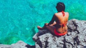 Une femme de dos en maillot de bain avec un léger excès de graisse au niveau des poignées d'amour