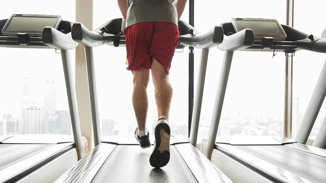 Photo d'un homme de dos courant sur un tapis de course à pied